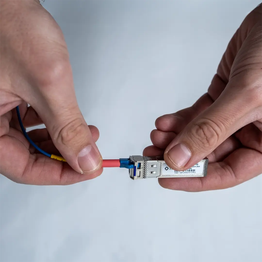 Henkilö liittää sinisen valokuitukaapelin SFP-moduuliin työntämällä liittimen varovasti paikalleen, kunnes se napsahtaa kiinni.